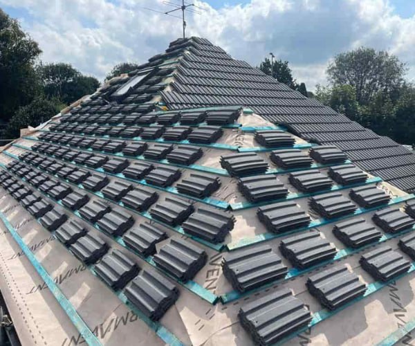 This is a photo of a new hip roof being installed. New felt, battens, and grey tiles have been installed, also a new velux window. Works carried out by JYT Roofing Hitchin